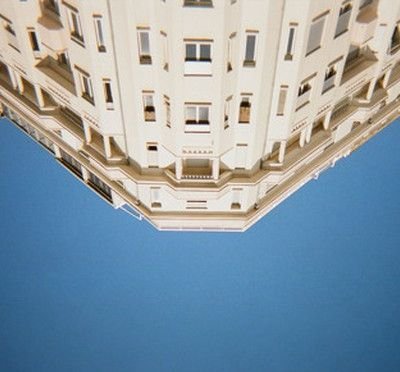 Upward view of a cream-colored Haussmann-style building corner against a clear blue sky, illustrating Kid Francescoli's single "Don't Get on the Plane"