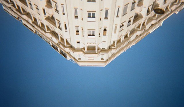Upward view of a cream-colored Haussmann-style building corner against a clear blue sky, illustrating Kid Francescoli's single "Don't Get on the Plane"